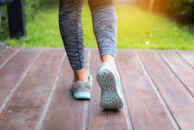 Low section of woman wearing sports shoes and leggings while jogging in park