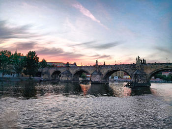 Arch bridge over river against sky during sunset
