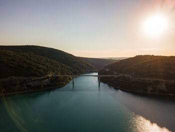 Scenic view of lake and bridge against sky during golden hour