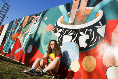 Portrait of a smiling young woman sitting on graffiti