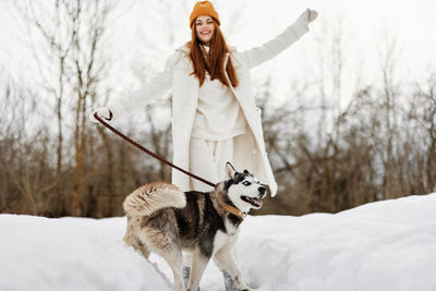 Portrait of young woman with dog on snow covered land