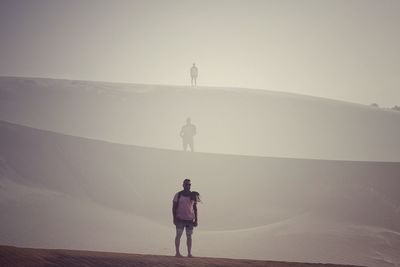 Rear view of man standing on mountain against sky