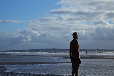 Rear view of man looking at sea against sky