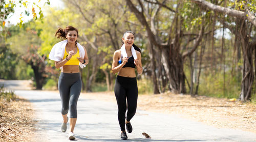 Full length of woman with arms raised against trees