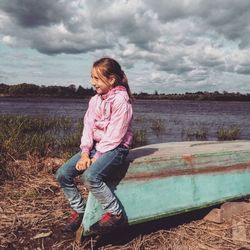 Full length of girl sitting on boat against sky