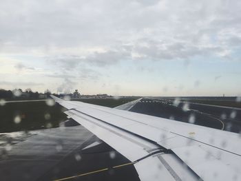 Cropped image of airplane against cloudy sky