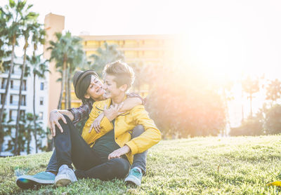 Lesbian couple embracing while sitting on field