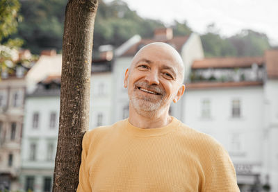 Happy senior man wearing a yellow sweater, looking content and smiling