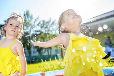 Two little sisters in paddling pool in the garden