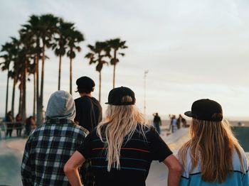 Rear view of people at beach against sky