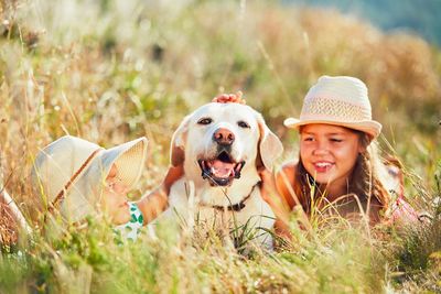 Siblings stroking dog on grassy field