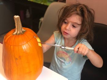 Close-up of girl holding pumpkin at home