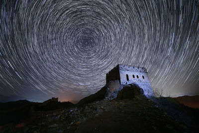 Low angle view of historic building against star trail at night