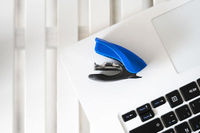 Blue stapler on top of a white laptop.