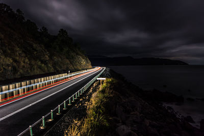 Light trails on road against sky at night