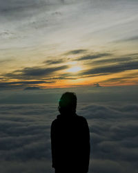 Rear view of silhouette man standing against sky during sunset