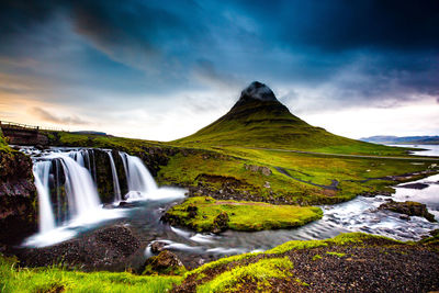 Scenic view of waterfall against cloudy sky