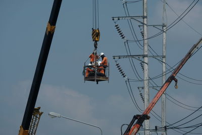 Low angle view of worker working against sky