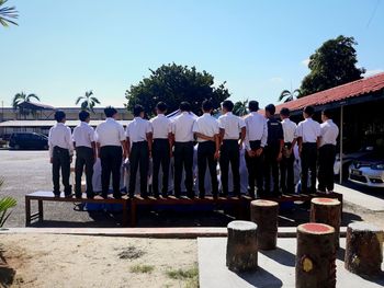 Rear view of people standing in row against sky