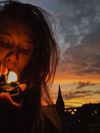 Close-up of woman against cloudy sky during sunset