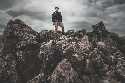 Man standing on rock formation against sky