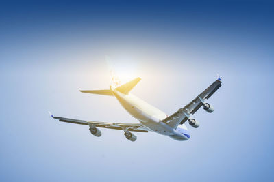 Low angle view of airplane flying against clear blue sky