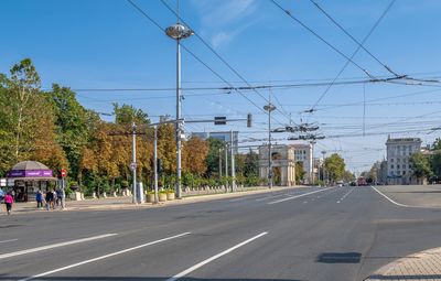 Road by trees against sky in city
