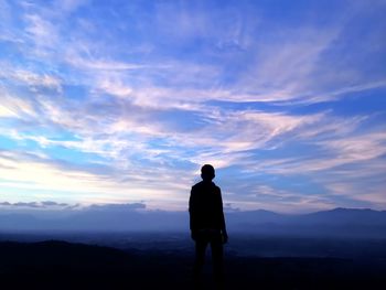 Silhouette man standing on mountain during sunset