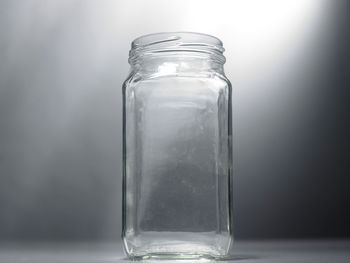 Close-up of empty glass jar against gray wall