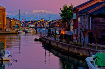 Sailboats moored on lake by buildings in city against sky