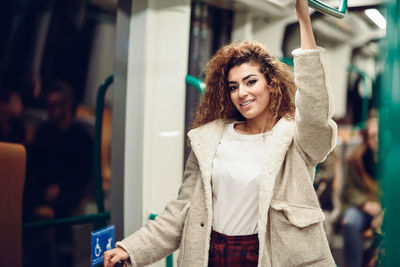 Portrait of smiling young woman standing in train