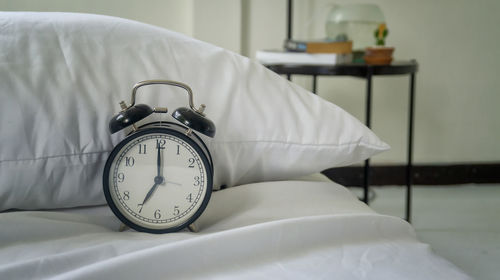 Close-up of alarm clock on bed