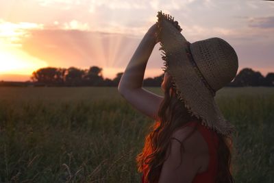 Woman wearing hat against sky during sunset