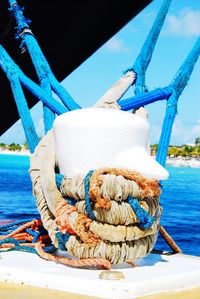 Close-up of rope tied to railing against blue sea