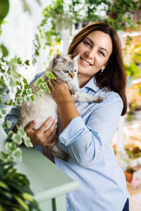 Portrait of young woman holding cat