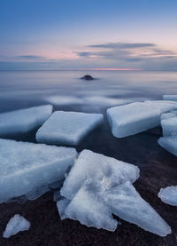 Frozen sea against sky during sunset