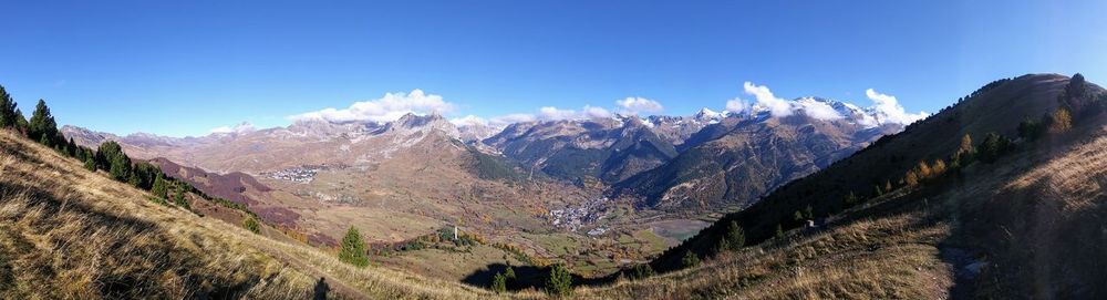Panoramic view of landscape and mountains against blue sky