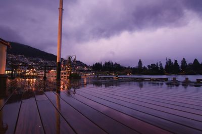 Pier on river against cloudy sky