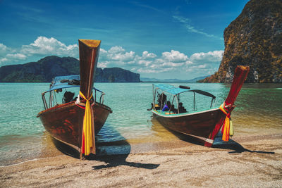 Boat moored on shore by sea against sky