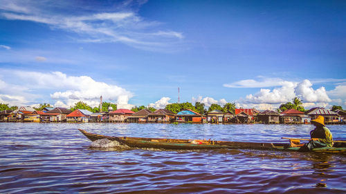 People on boat sailing in river against blue sky