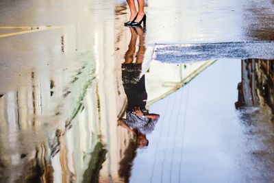 Low section of man standing on wet beach