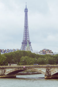 Low angle view of bridge over river against cloudy sky