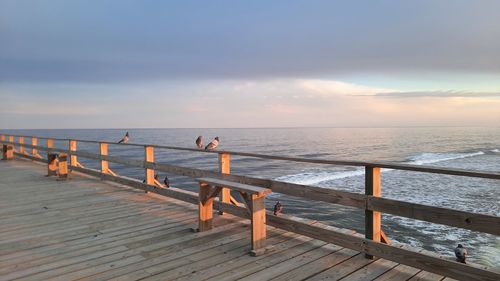 Pier over sea against sky during sunset