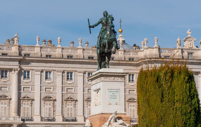 Statue in city against sky