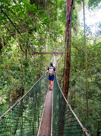 Rear view of person crossing rope bridge