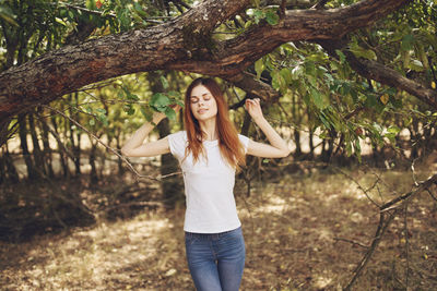 Young woman standing against trees