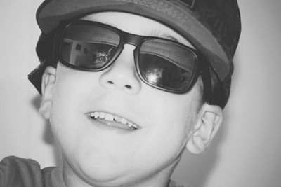 Close-up portrait of smiling boy wearing sunglasses against wall