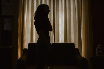 Silhouette woman sitting on chair at home