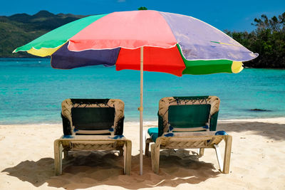 Deck chairs on beach against sky