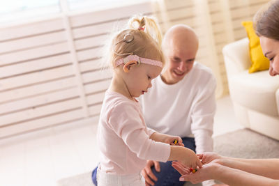 Rear view of mother and daughter playing with toy blocks while sitting on floor at home